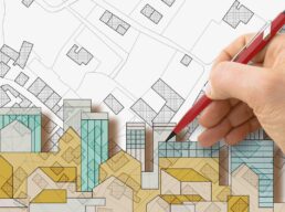Architect drawing a residential building over an imaginary cadastral map of territory with buildings, fields and roads