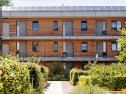 Multi-family House or Modern Apartment Building with Solar Panel, Wooden Facade and Community Garden Landscape is Trendy of Urban Construction in Europe, Germany. Eco Housing concept.